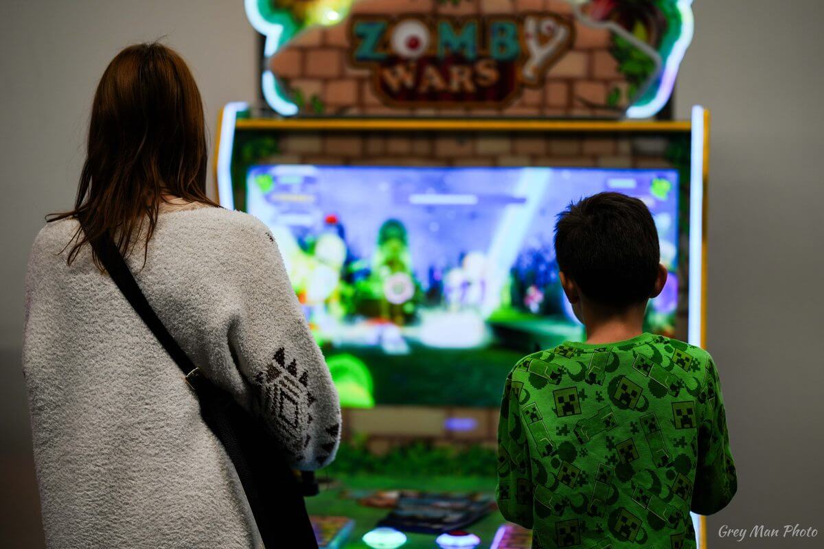Enfant et adulte devant une borne d'arcade à Animasia