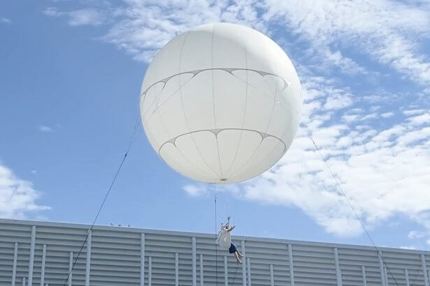 Artiste suspendue sous un ballon géant blanc, spectacle aérien du FAB, festival des arts de Bordeaux Métropole
