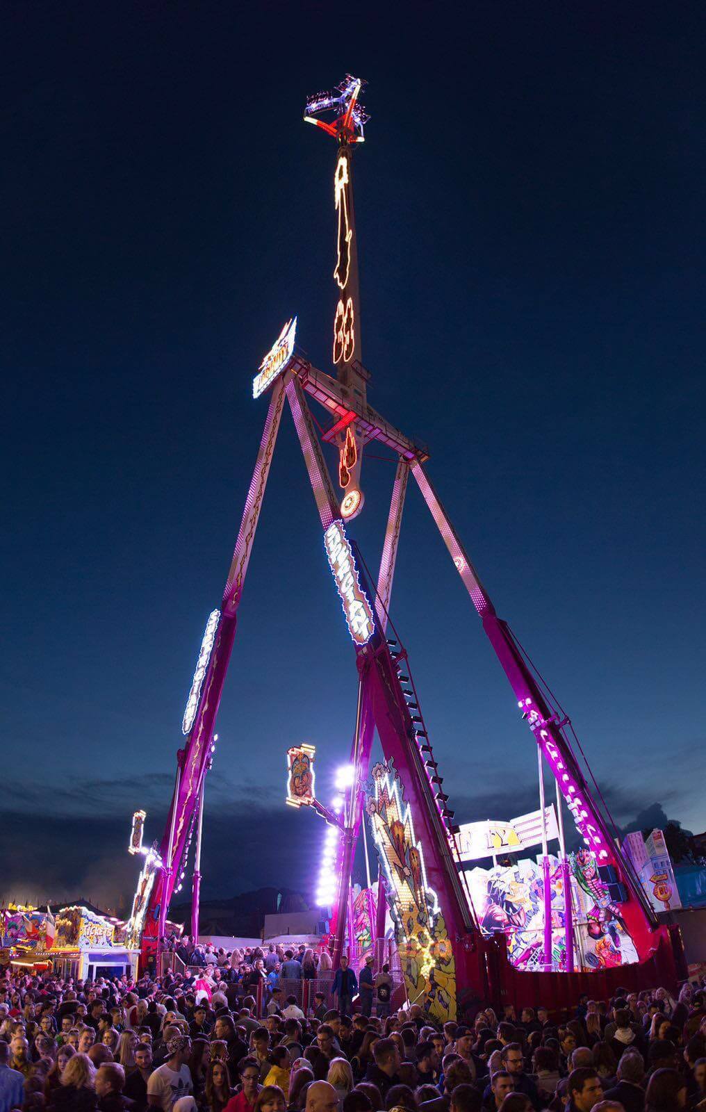 Le manège Infinity Inversion illuminé de nuit au-dessus de la foule