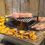 Côtes de bœuf, potatoes et camembert rôti sur la plancha d'un brasero carré PFC, flamme au centre