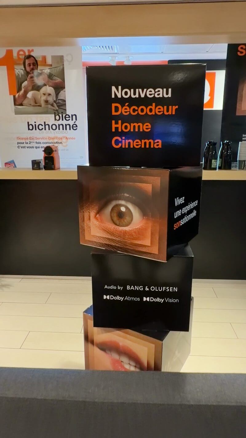 Détail du totem Orange avec les logos Bang & Olufsen, Dolby Atmos et Dolby Vision