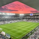 Le Stade Atlantique de Bordeaux plein, pelouse et tribunes sous un ciel rose au coucher du soleil