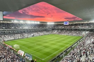 Le Stade Atlantique de Bordeaux plein, pelouse et tribunes sous un ciel rose au coucher du soleil