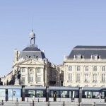 Place de la Bourse et tramway au bord du Miroir d'eau à Bordeaux sous un ciel bleu