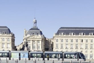 Place de la Bourse et tramway au bord du Miroir d'eau à Bordeaux sous un ciel bleu