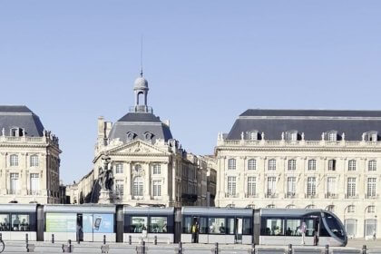 Place de la Bourse et tramway au bord du Miroir d'eau à Bordeaux sous un ciel bleu