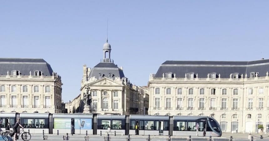 Place de la Bourse et tramway au bord du Miroir d'eau à Bordeaux sous un ciel bleu