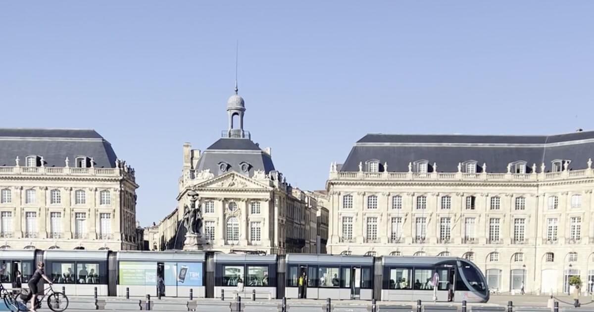 Place de la Bourse et tramway au bord du Miroir d'eau à Bordeaux sous un ciel bleu