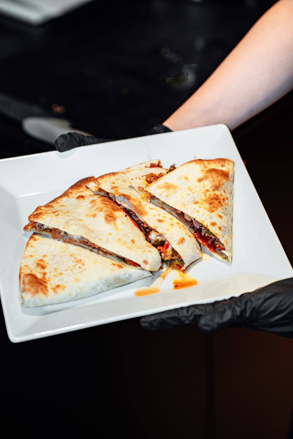 Quesadilla coupée en parts sur une assiette blanche, chez Nachos à Mérignac