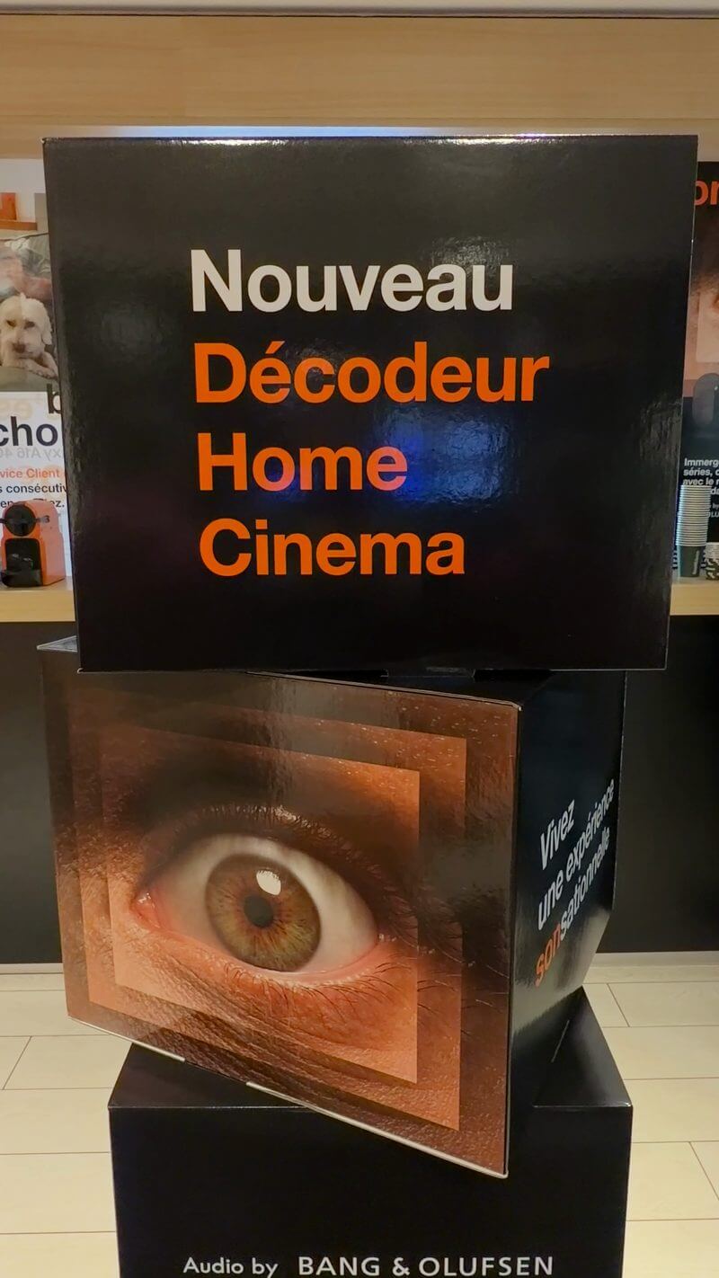 Totem noir et orange « Nouveau Décodeur Home Cinema » avec un grand œil, dans la boutique Orange de Bordeaux